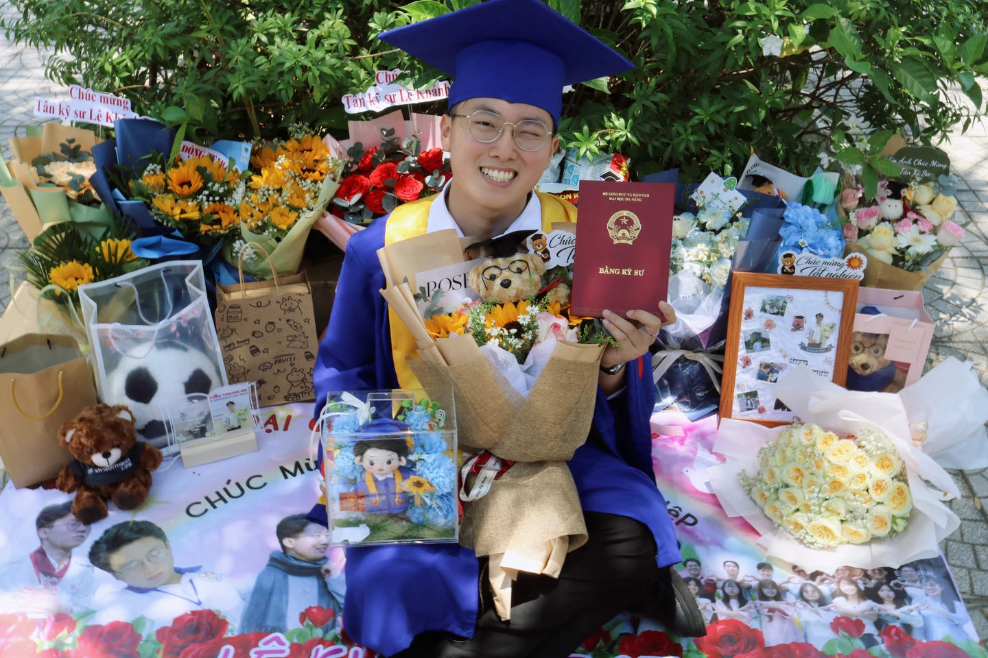 Holding my engineering diploma among graduation flowers and gifts